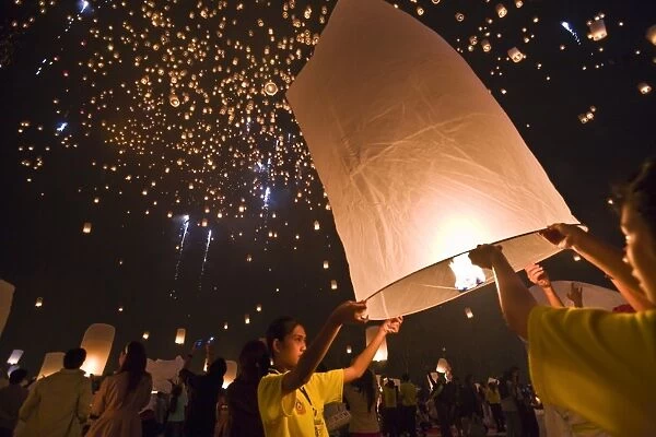 Thailand, Chiang Mai, San Sai. Revellers launch khom loi (sky lanterns) into the night sky during the Yi Peng festival. The ceremony is a Lanna (northern Thailand) tradition and coincides with Loy Krathong festivities. The khom loi are