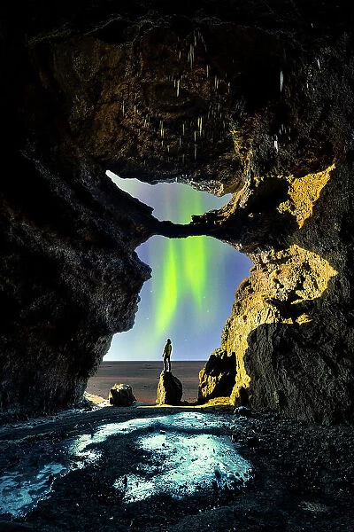 A tourist in Gigjagja cave during night with northern lights, Sudurland, Iceland(MR)