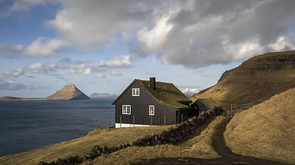 A traditional Faroese house in Velbastaður. The island of Koltur in the background. Faroe Islands