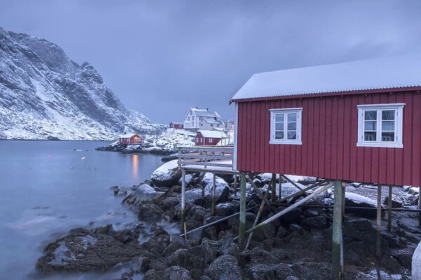 Typical fishermen houses called rorbu in the snowy landscape at dusk Nusfjord Nordland