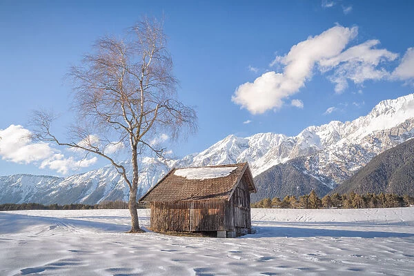 A typical wooden cabin in the snowy fields of Wildermieming, Mieming, Sonnenplateau