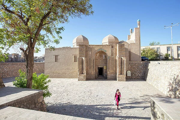 Uzbekistan, Bukhara, a woman walks past a small mosque in central Bukhara