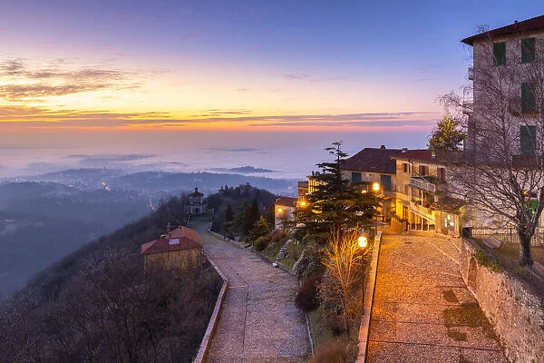 View of the old town of Santa Maria del Monte in winter at sunrise with the fog on Varese