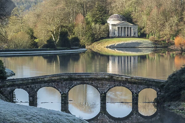 View across Turf Bridge and Garden Lake to the Pantheon, in the grounds of Stourhead, Wiltshire, England. Winter (January) 2022