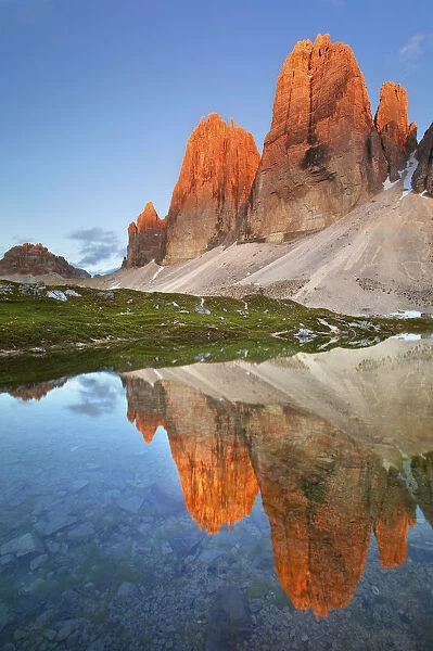 A waterhole its reflecting the Lavaredos Three Peaks, illuminated by the
