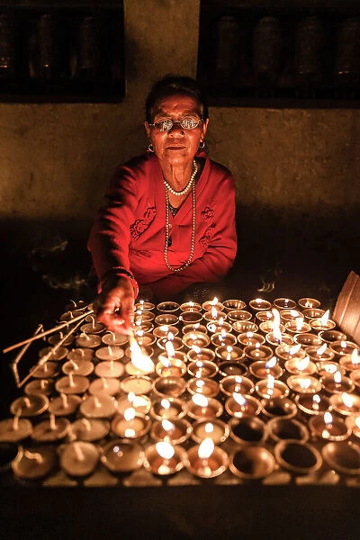 Woman lighting devotional candles in temple at Swayambhunath Stupa, Kathmandu, Nepal