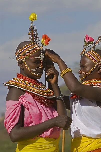 Two young Samburu girls help each other preparing for a celebration