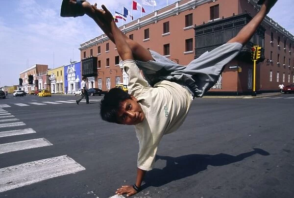 A youth performs an armstand on the streets of Trujillo