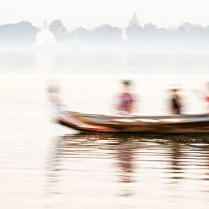 A boatman taking tourists in his traditional wooden boat across the Taungthaman Lake