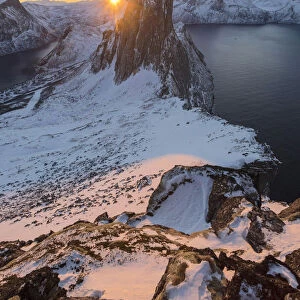 First lights of sunrise on Mount Segla and Mefjorden framed by the frozen sea seen