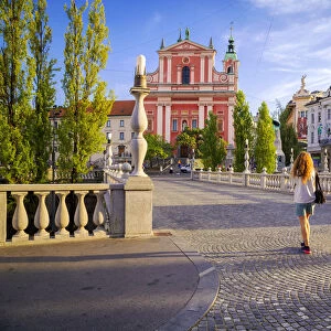 A girl walking in the old town of Ljubljana, with the Triple Bridge and the iconic