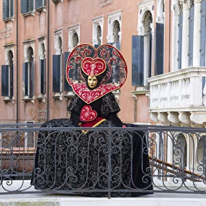 Heart-shaped costume standing on a bridge at the Venice Carnival, Venice, Italy