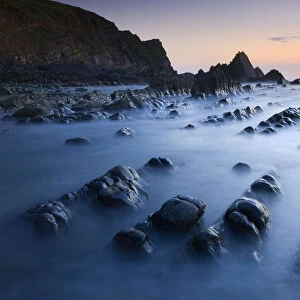 High tide gradually submerges the rocky shores of Blegberry Bay at sunset, Hartland