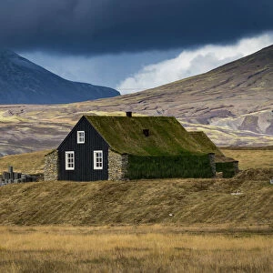 House with roof covered by grass against mountains, South Iceland, Iceland