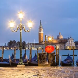 Italy, Veneto, Venice. Woman with red umbrella on Riva degli Schiavoni at dawn (MR)