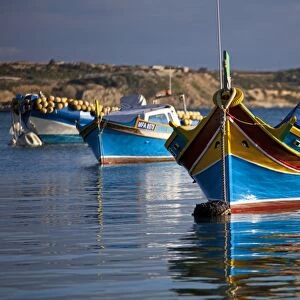 Malta, Europe; Colourful traditional Maltese boats known locally as luzzu in the village of Marsaxlokk which is still based around the fishing industry. The boats have two eyes in the bow which according to legend might represent those
