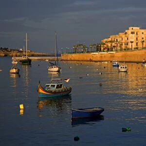 Malta, Europe; Colourful traditional wooden boats in the placid bay of the former fishing village