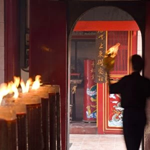 Man with lit paper in Chinese temple