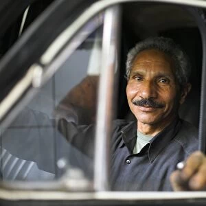 A mechanic sits inside a car at his garage in the district of Zamalek
