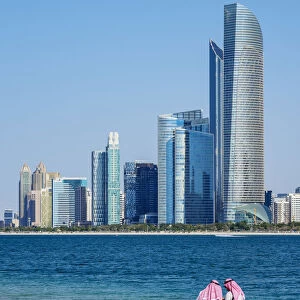 Two men wearing thawb on the beach and City Center Skyline, Abu Dhabi, United Arab