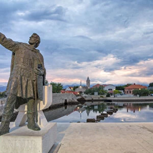 monument of Branimir of Croatia in Nin, on the background the old bridge that connects