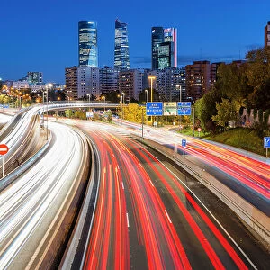 Night view of car light trails on an urban highway with Four Towers (Cuatro Torres) business district in the background, Madrid, Spain
