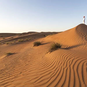 Oman, Wahiba Sands. Man with omani dress on the sand dunes at sunrise (MR)