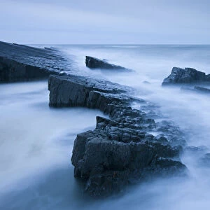 Swiling tide around jagged rocks on Spekes Mill Mouth beach, Hartland, Devon, England