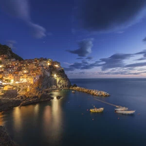 Twilight in Manarola, Cinque Terre, the most beautiful moment of the day when the lights of the town come