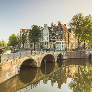 Typical houses reflecting in Keizergracht water canal at sunrise in Amsterdam