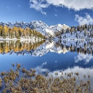 The still water of Lake Malghette reflecting the Brenta Dolomites peaks in autumn