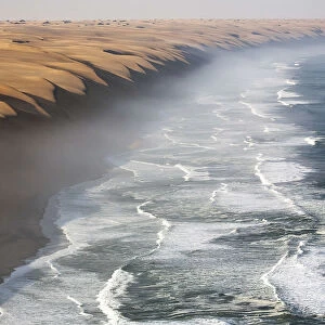 The waves of the Atlantic Ocean crashing against the sandy wall of the Namib desert