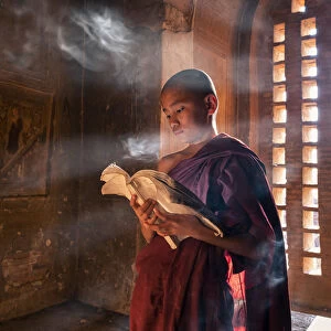 A young monk reading by a window inside a temple, UNESCO, Bagan, Mandalay Region, Myanmar