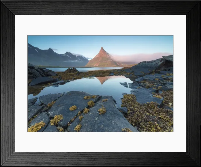 Framed Print : The rocky peak of Volanstinden lighted up by the midnight sun is reflected in blue Framed Print : The rocky peak of Volanstinden lighted up by the midnight sun is reflected in blue