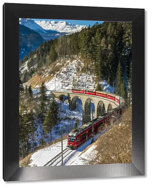 The famous red train of Albula mountain railway passing through a scenic winter alpine