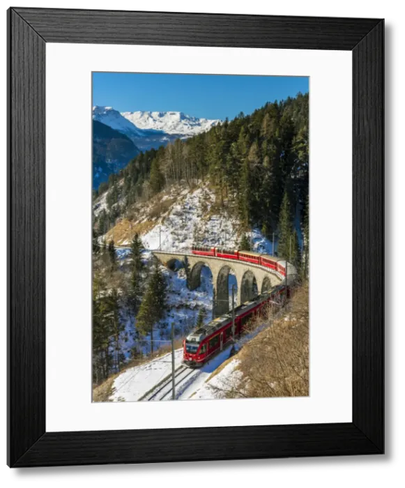 Framed Print : The famous red train of Albula mountain railway passing through a scenic winter alpine Framed Print : The famous red train of Albula mountain railway passing through a scenic winter alpine