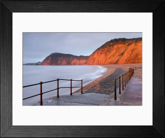 Framed Print : Early morning sunlight glows against the distinctive red cliffs of High Peak, viewed