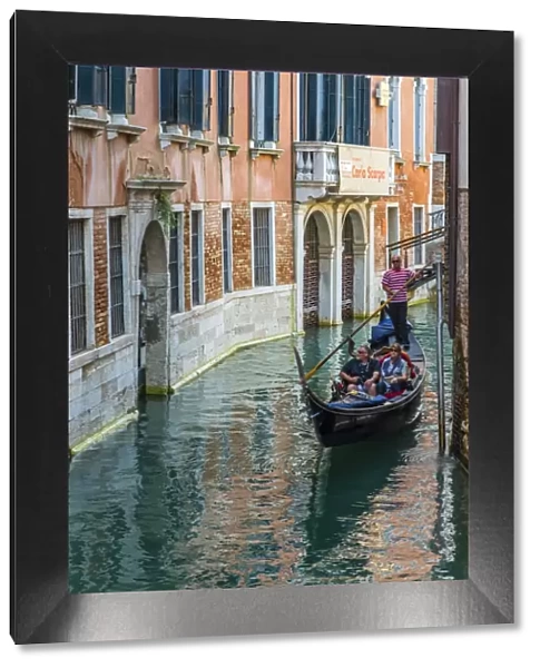 Gondola boat passing through a narrow canal, Venice, Veneto, Italy