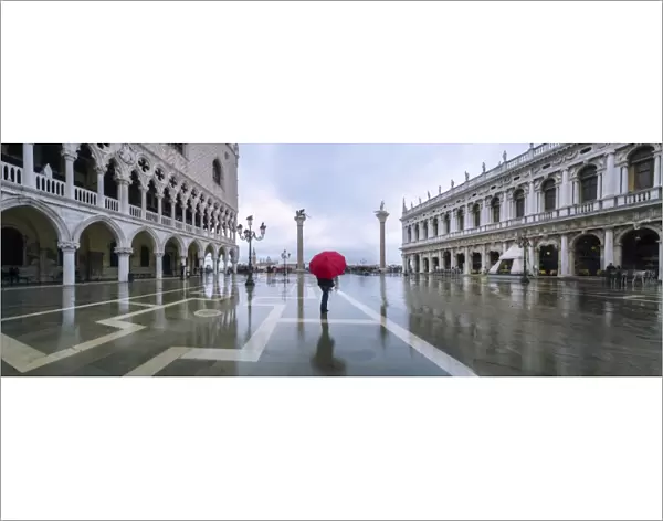 Italy, Veneto, Venice. Woman with red umbrella in front of Doges palace with acqua alta