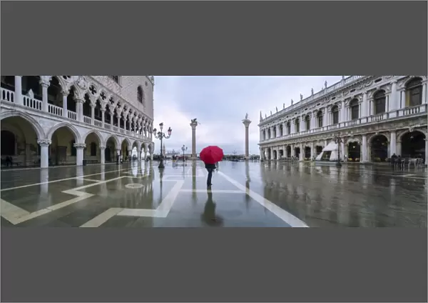 Italy, Veneto, Venice. Woman with red umbrella in front of Doges palace with acqua alta