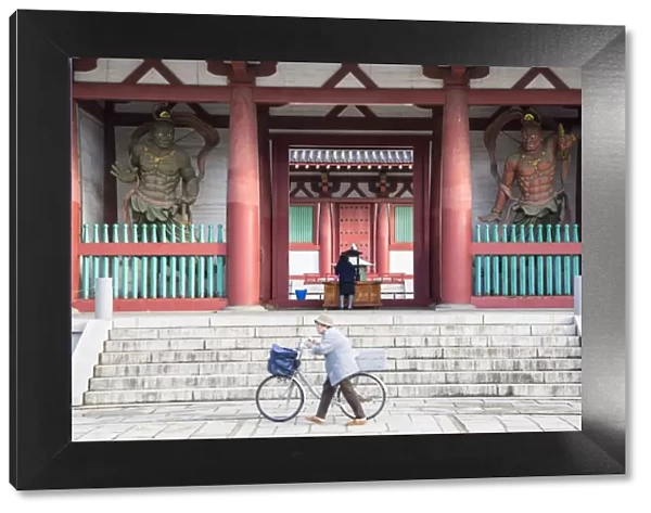 Woman pushing bicycle past Shitenno-ji temple, Tennoji, Osaka, Kansai, Japan