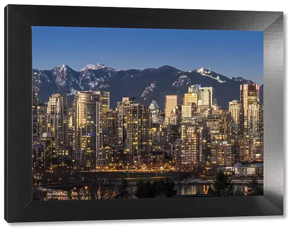 Downtown skyline with snowy mountains behind at dusk, Vancouver, British Columbia, Canada