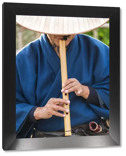 Japanese man playing traditional wooden flute, Kyoto, Japan