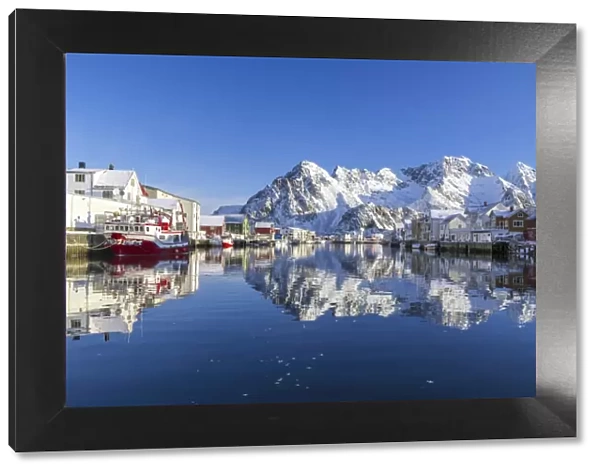 Houses and mountains reflected in the waters of Henningsvaer fjord. Lofoten Islands
