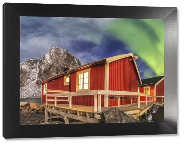 The green light of the aurora borealis lights up fishermans cabins