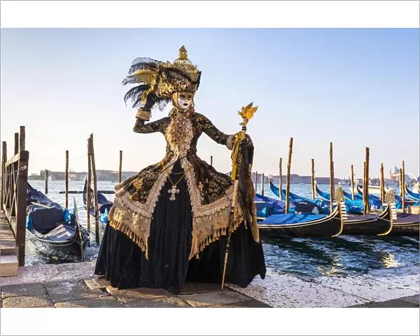 A woman in a magnificent costume poses in front of Gondolas during the Venice Carnival