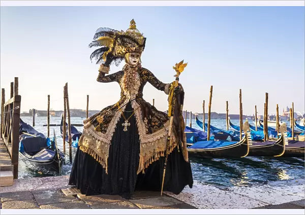 A woman in a magnificent costume poses in front of Gondolas during the Venice Carnival