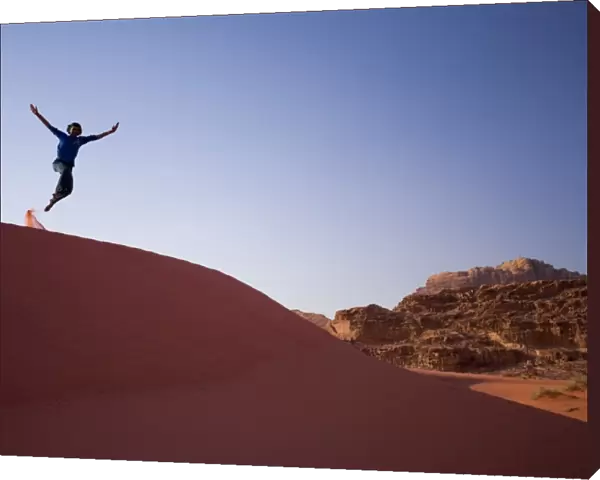 Person jumping off sand dune