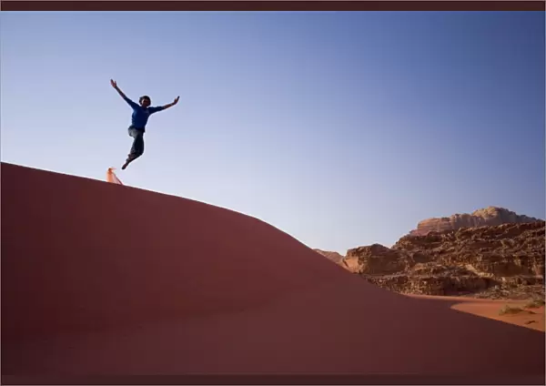 Person jumping off sand dune