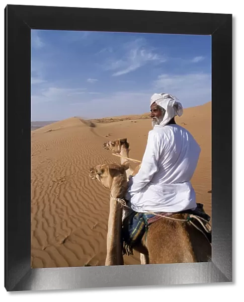 A Bedu rides his camel in the desert